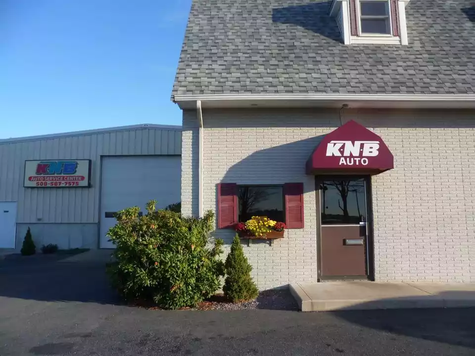 The KNB Auto storefront with its maroon awning and the KNB Auto Service Center garage sign